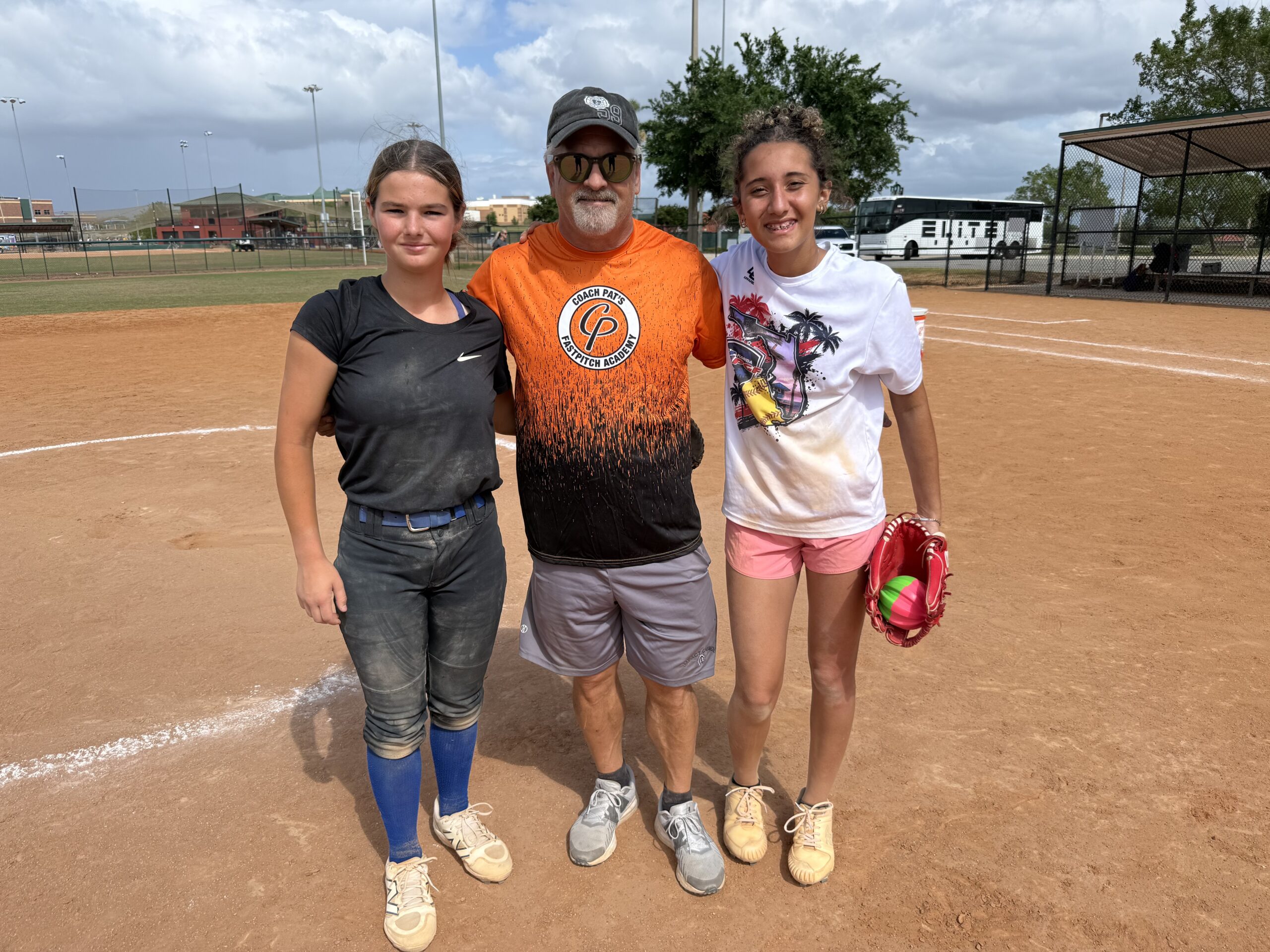 Coach with two young softball players on field
