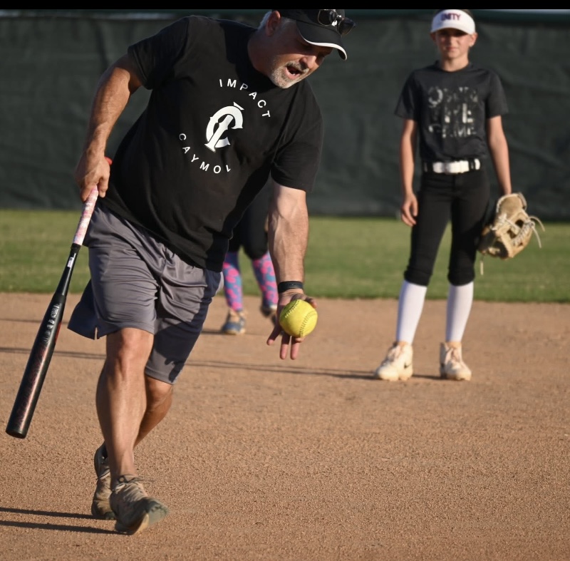 Coach rolling softball to young player