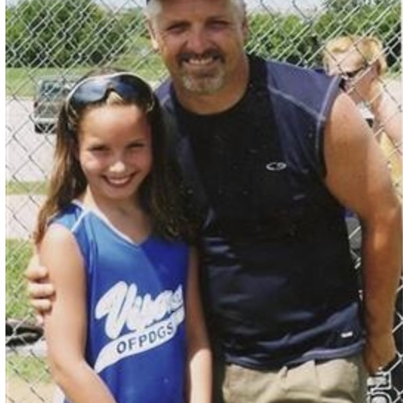Man and girl smiling at softball field